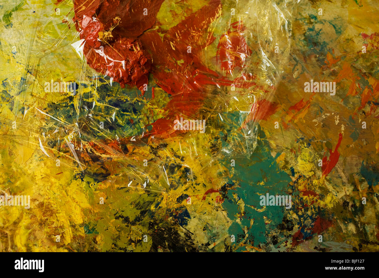 Artist palette shows shows a large blob of red paint covered with cellophane. Stock Photo