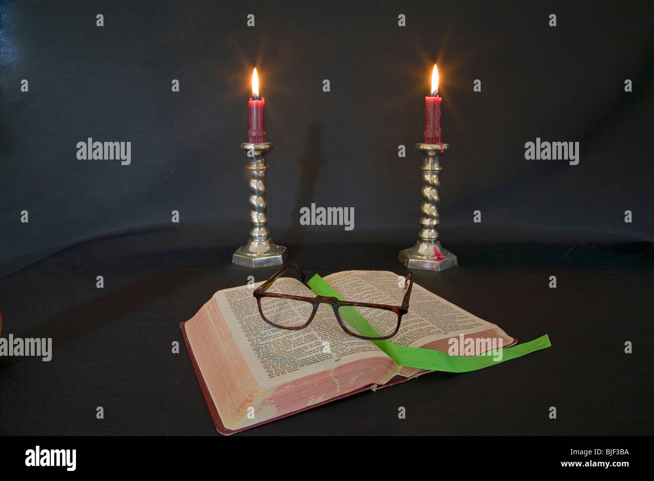 Lighted candles, reading glasses, and a good book. Stock Photo