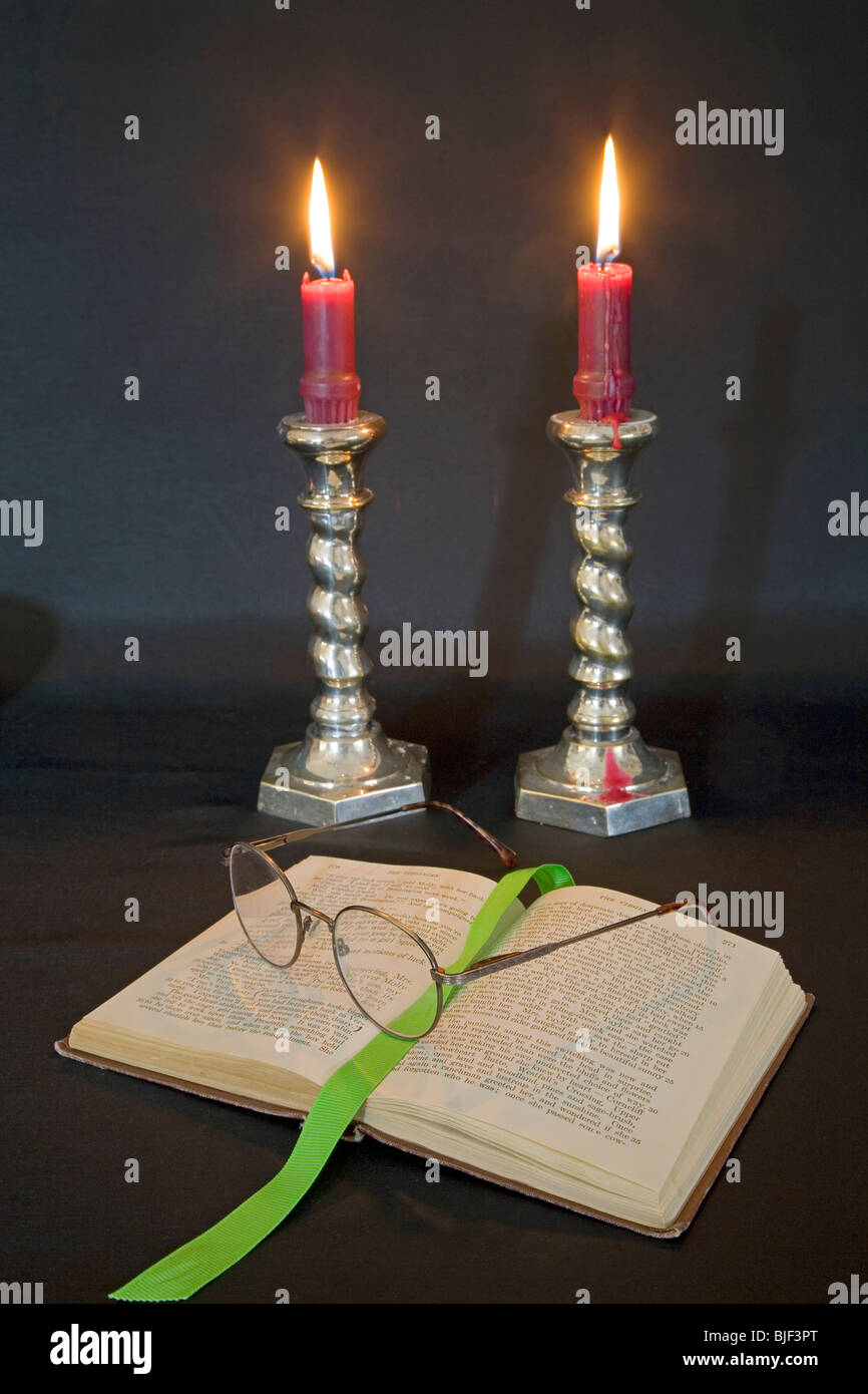 Lighted candles, reading glasses, and a good book. Stock Photo