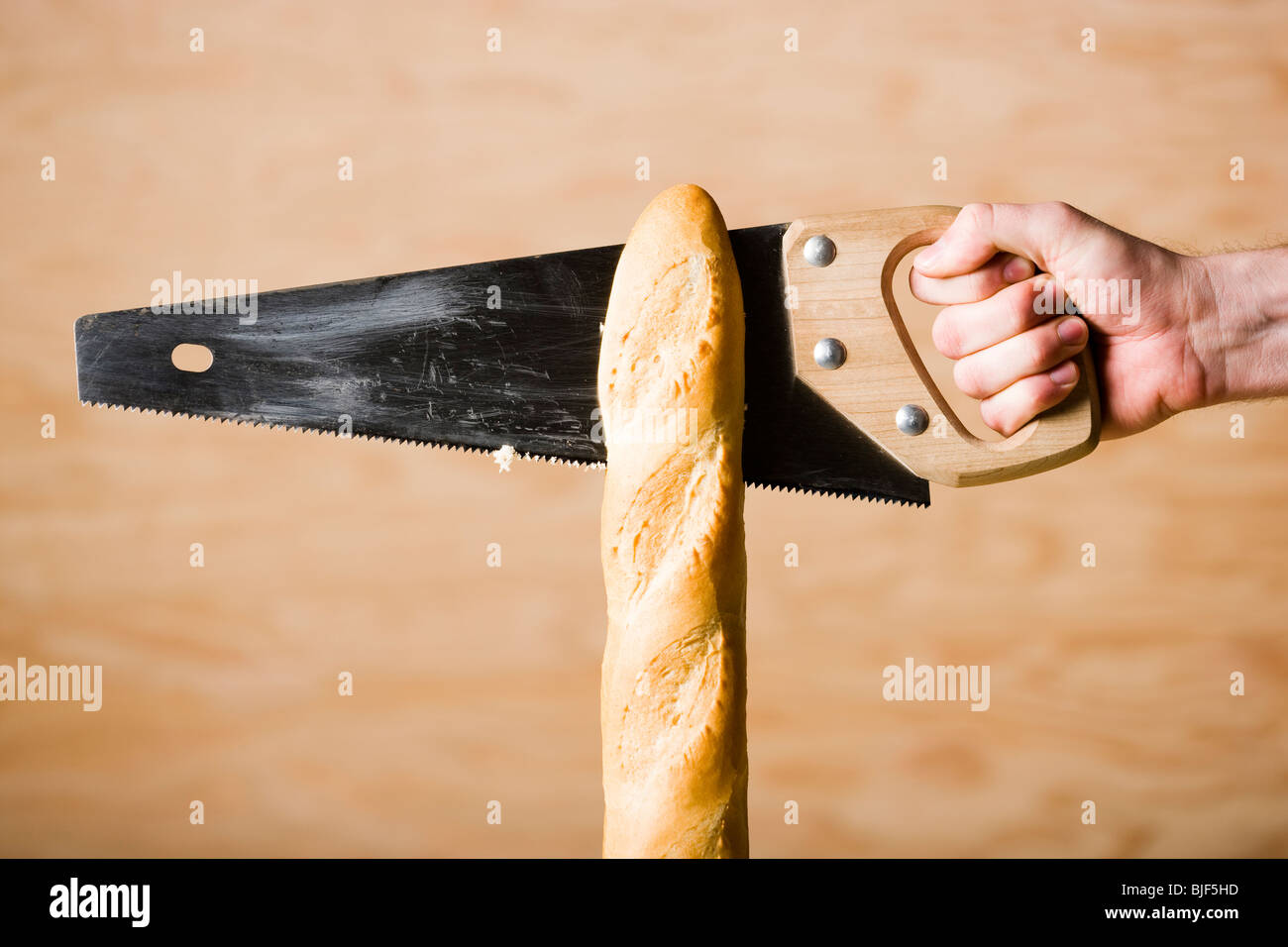 hand sawing a loaf of french bread Stock Photo