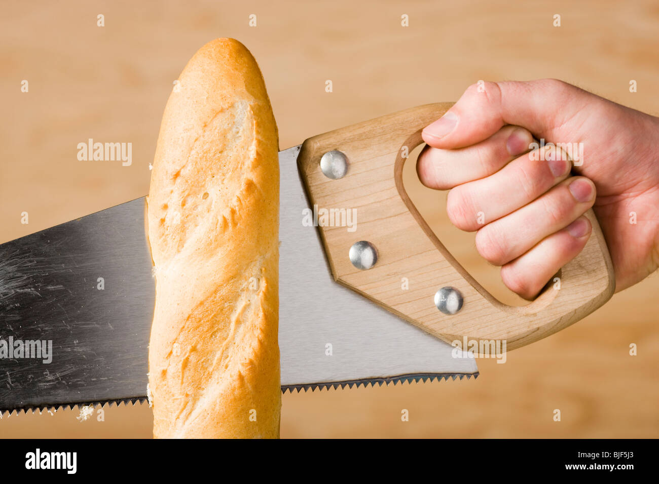 hand sawing a loaf of french bread Stock Photo