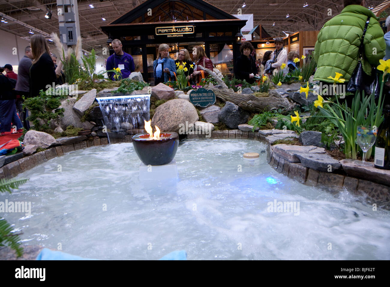 steamy hot tub artificial fire rock stone yellow flower green plant visitors buyers watching Stock Photo