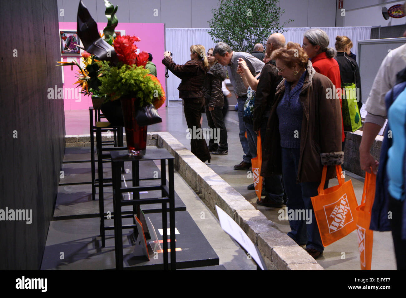 spectators gather around looking at the flower arrangements Stock Photo
