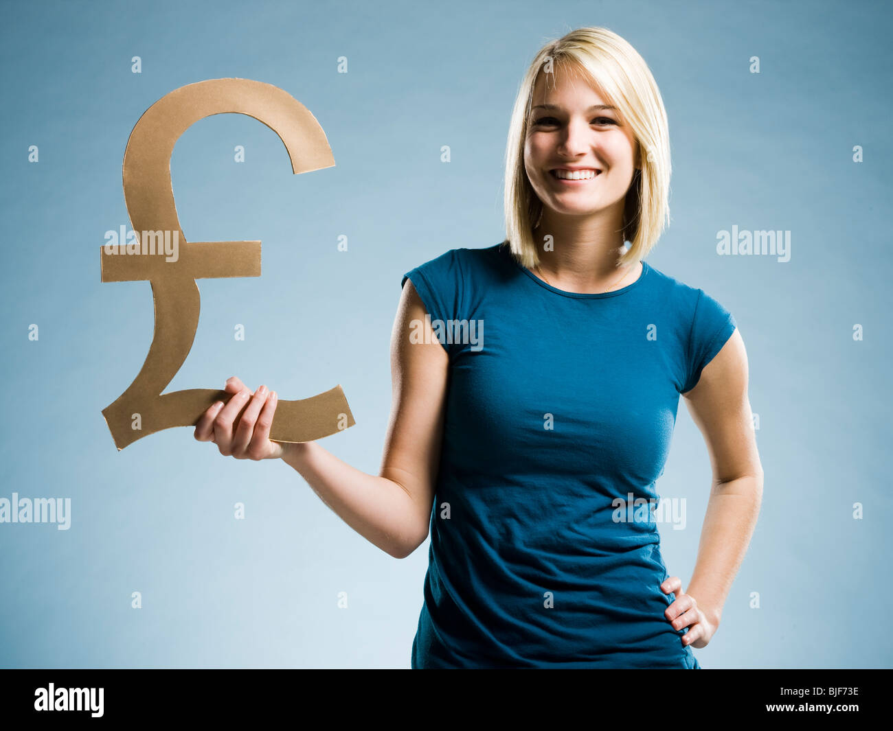 woman holding up a british pound symbol Stock Photo