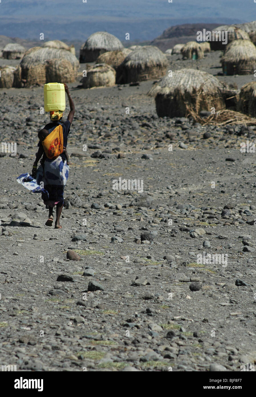 A women walks back to Loyangalani village with collected water. Lake Turkana, Eastern Kenya, Africa Stock Photo