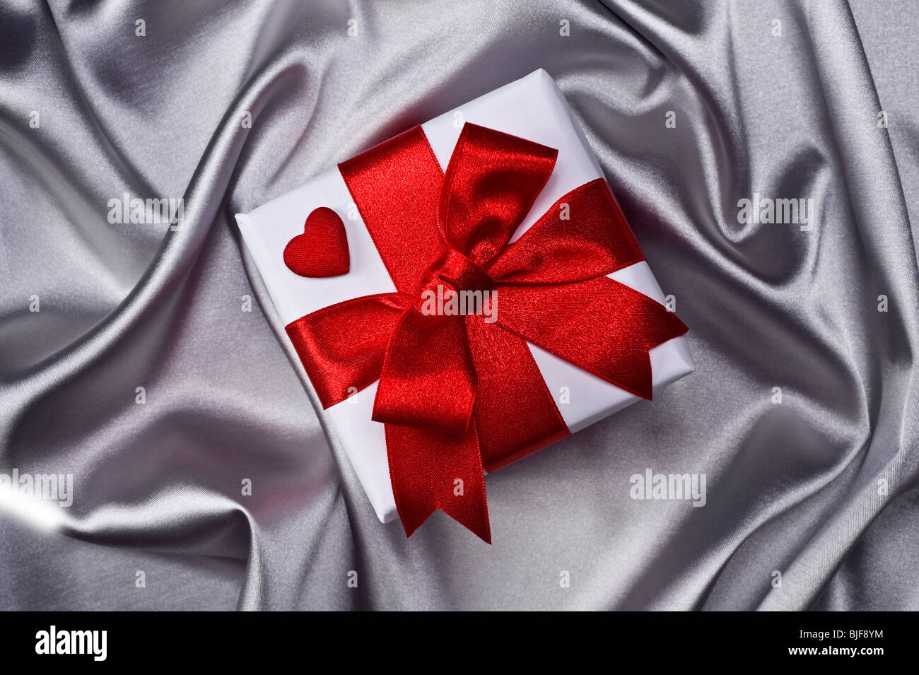 gift with decorative red ribbon on silver background Stock Photo