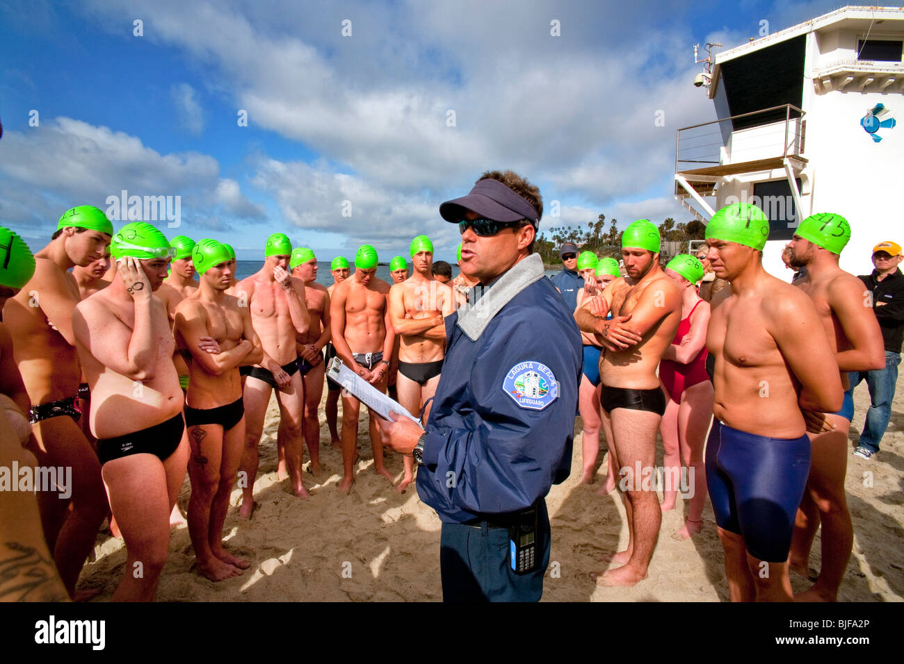 Wearing caps with their classification numbers, teen applicants for lifeguard jobs are briefed before their qualifying swim. Stock Photo