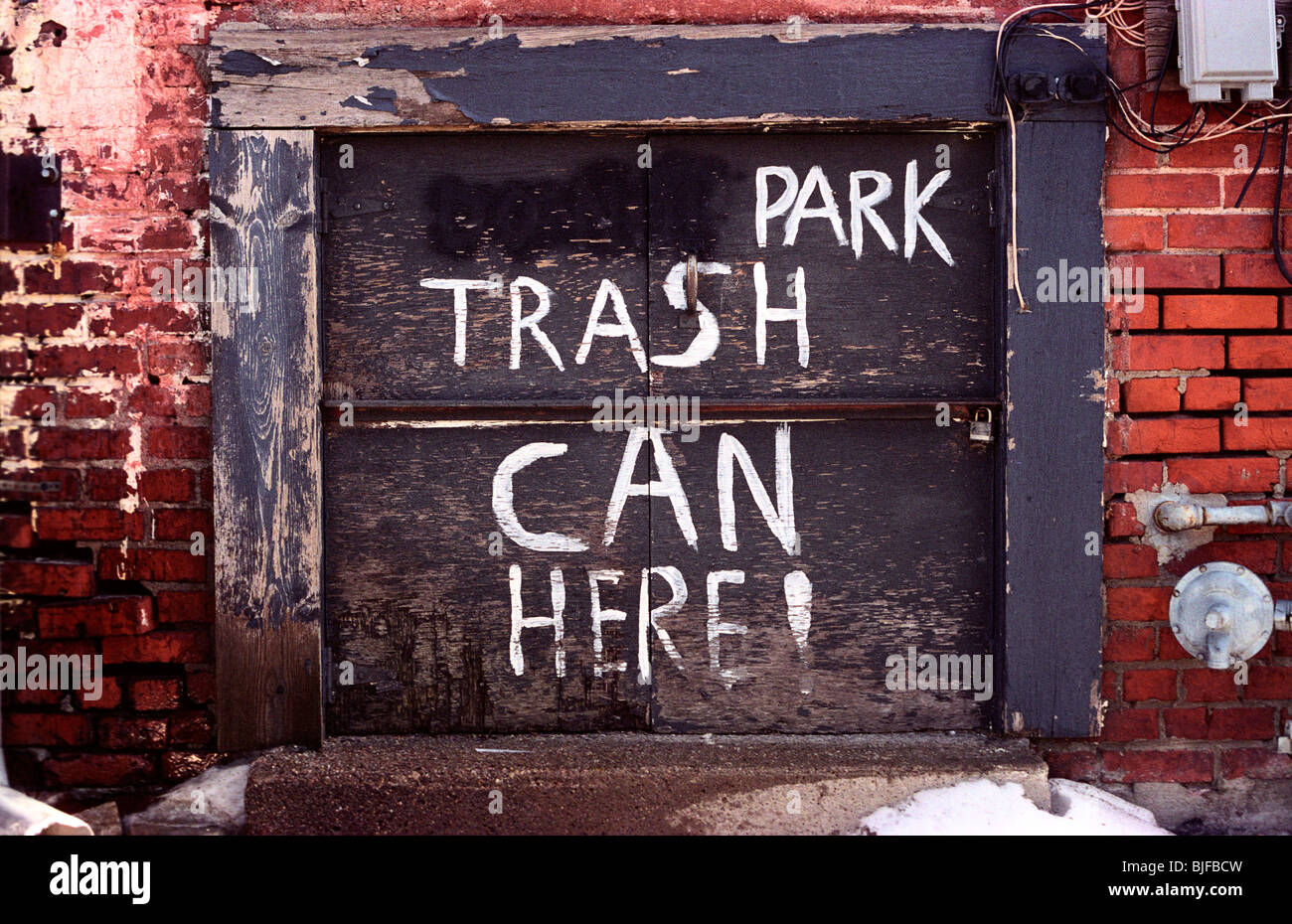 A rather odd 'PARK TRASH CAN HERE!' sign in an alleyway. Appears to have originally read 'DON'T PARK TRASH CAN HERE!' Stock Photo
