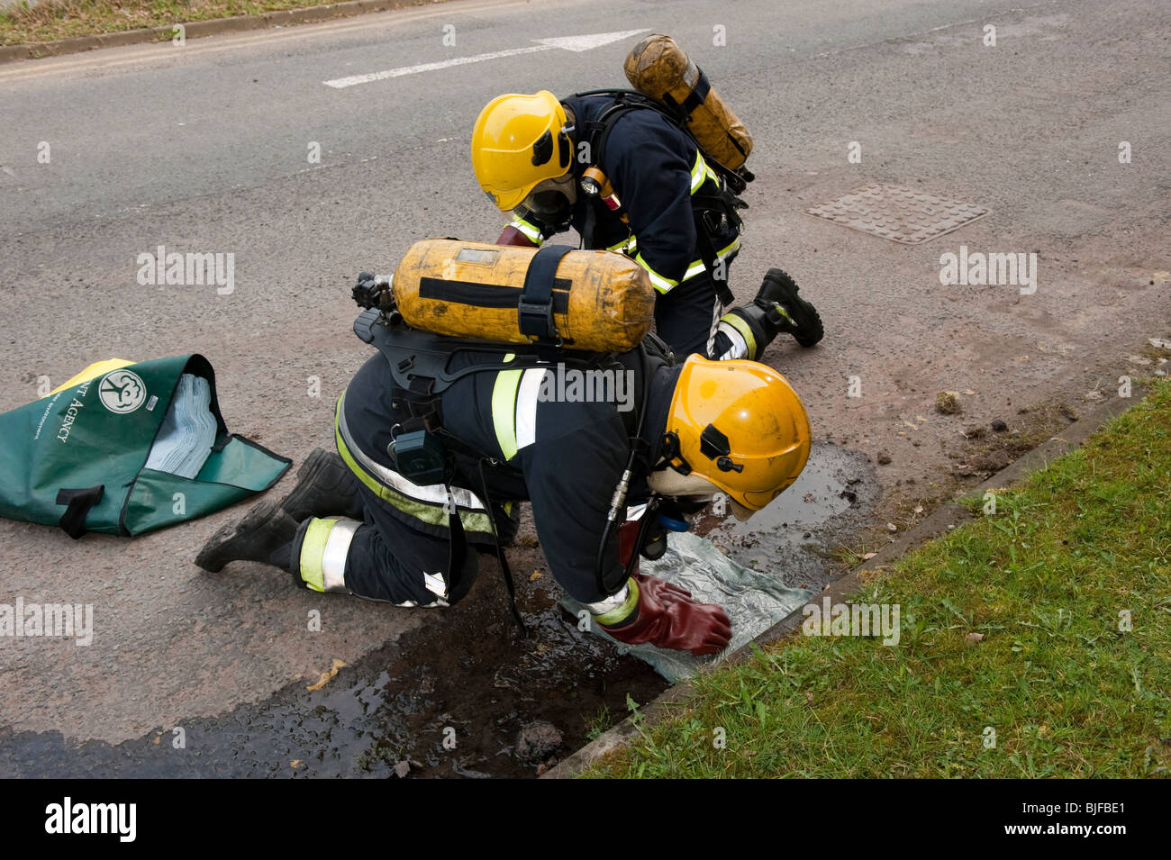 Two firemen stop chemicals leaking down drain with a Dammit chemical