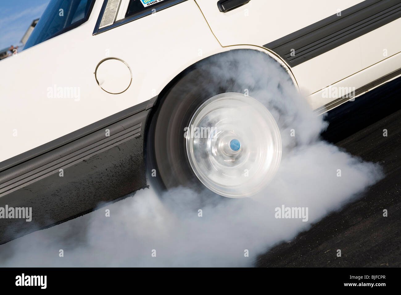 Close up of spinning car tire and wheel performing a smoking burnout Stock Photo