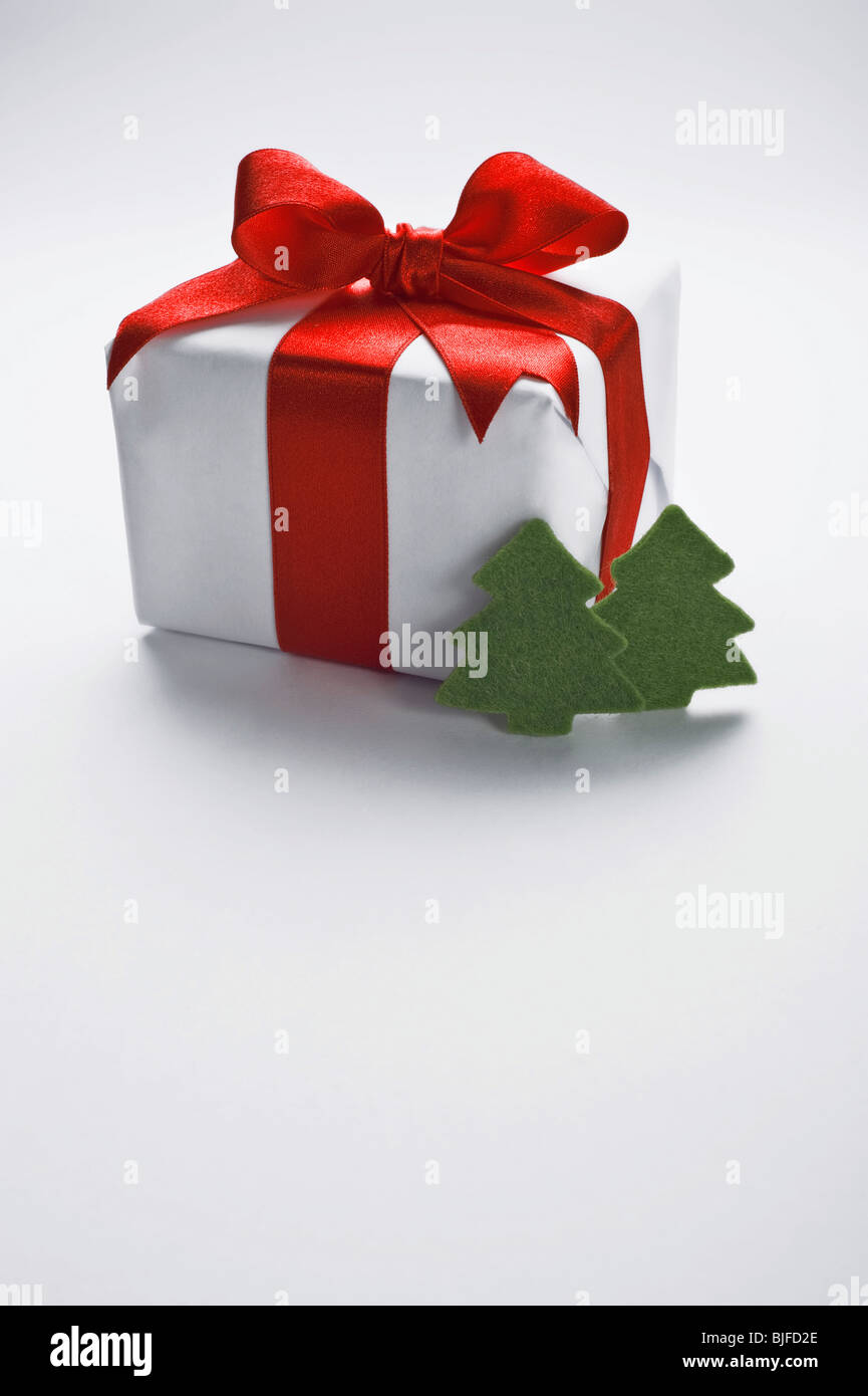 Christmas gift with decorative red ribbon and trees Stock Photo