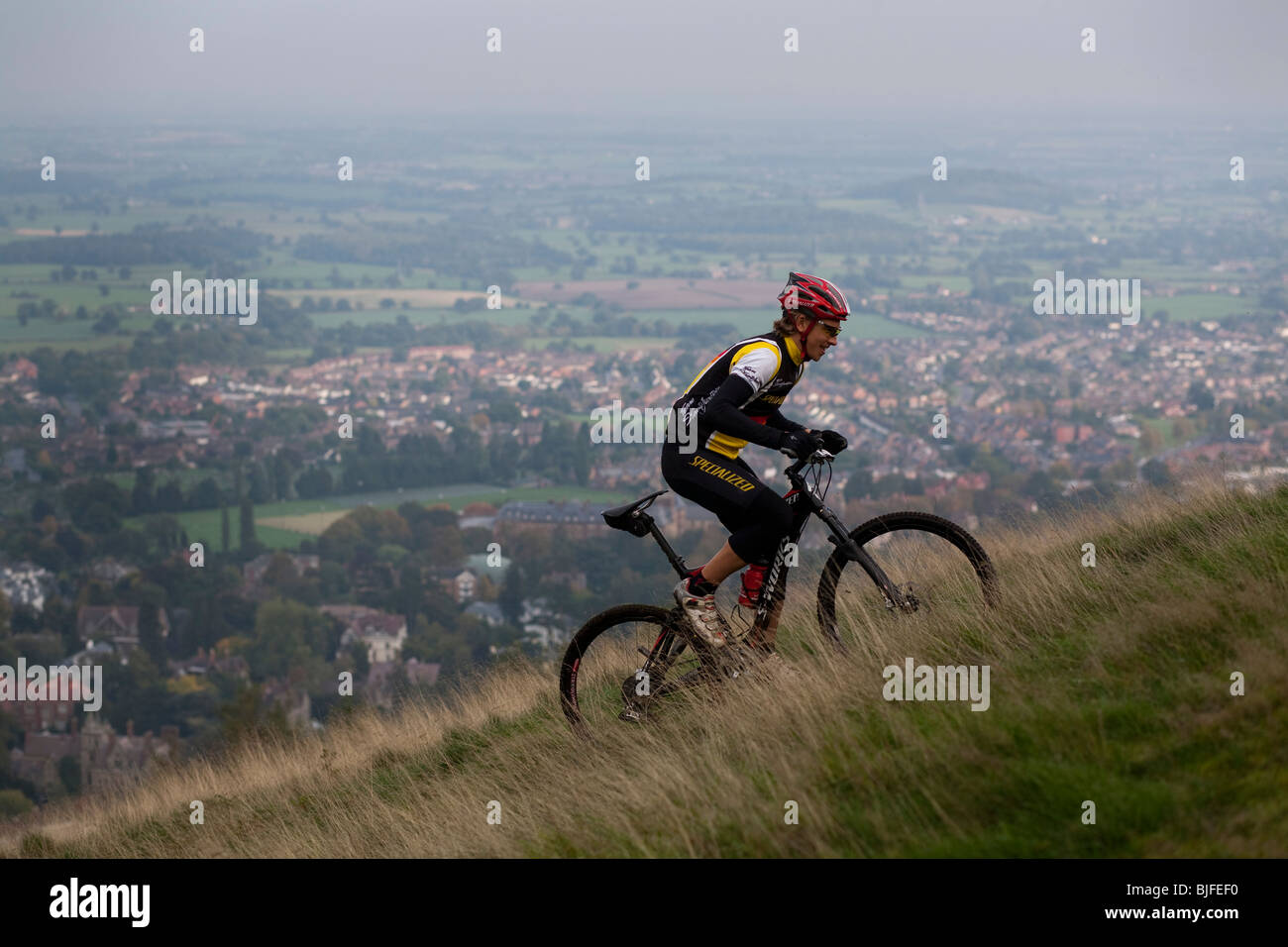 British mountain biker Liam Killeen rides up a hill above a village Stock Photo