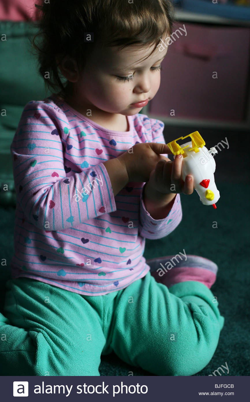 A 2 year old girl playing with a wind up chicken toy Stock Photo