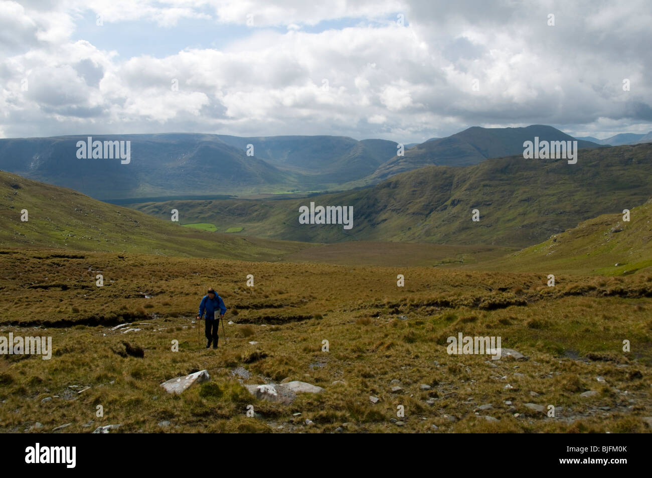 A walker in the Sheeffry Mountains, County Mayo, Ireland. The Maumtrasna plateau, Partry Mountains, in the distance. Stock Photo