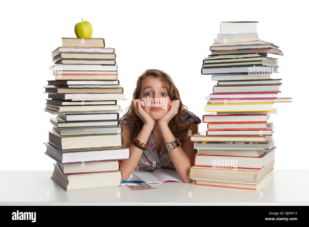 Teenage girl is making homework between a pile of heavy books Stock Photo
