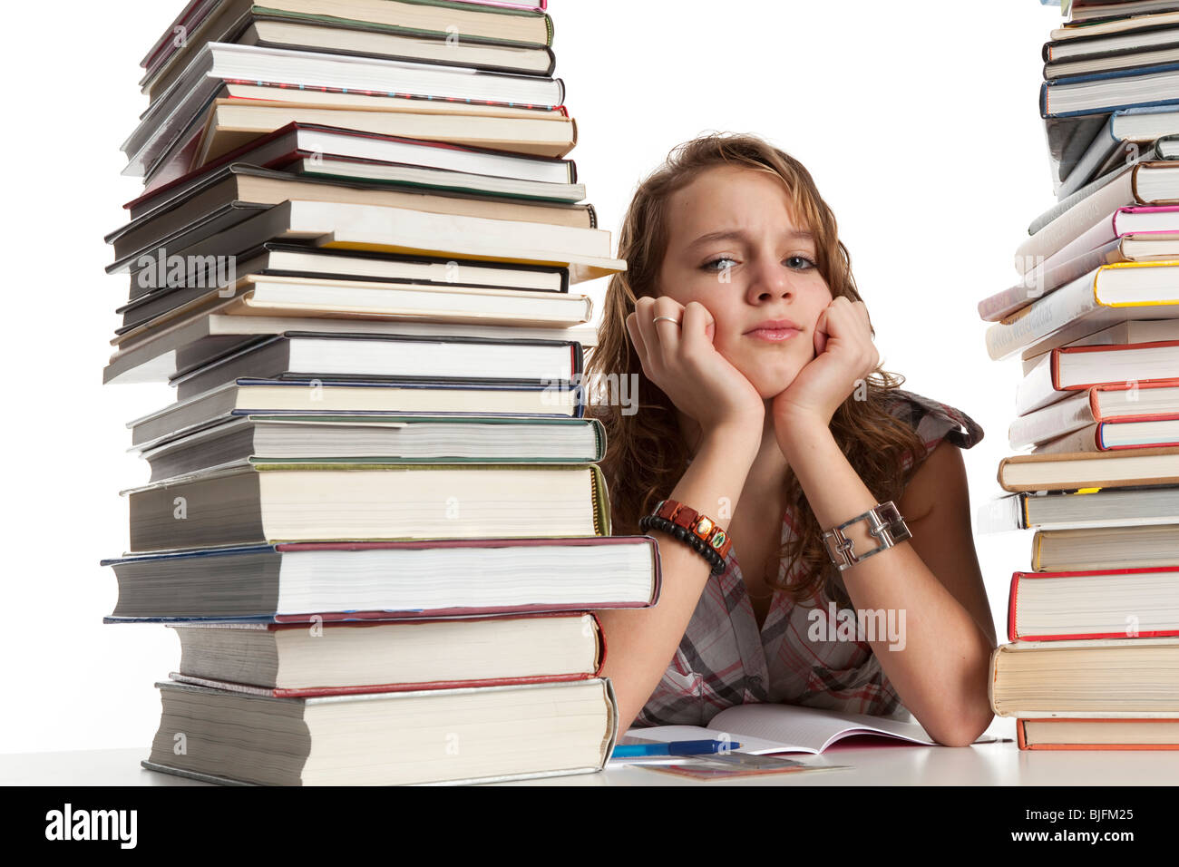 Teenage girl is making homework between a pile of heavy books Stock Photo