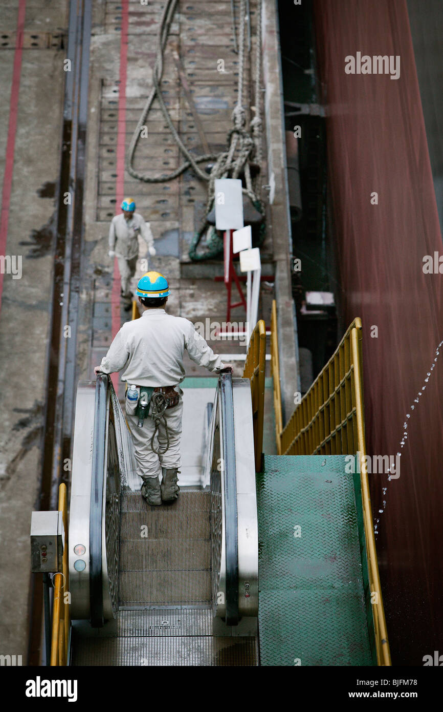 Man in an escalator at a huge shipyard in China. Stock Photo