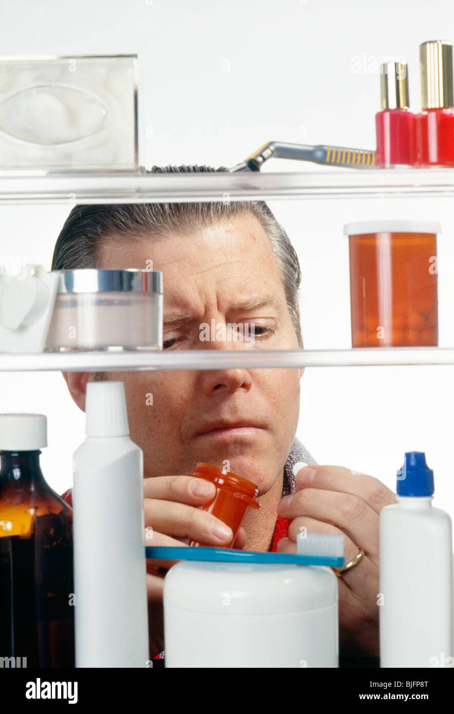 Man Taking Pill at Medicine Cabinet Stock Photo