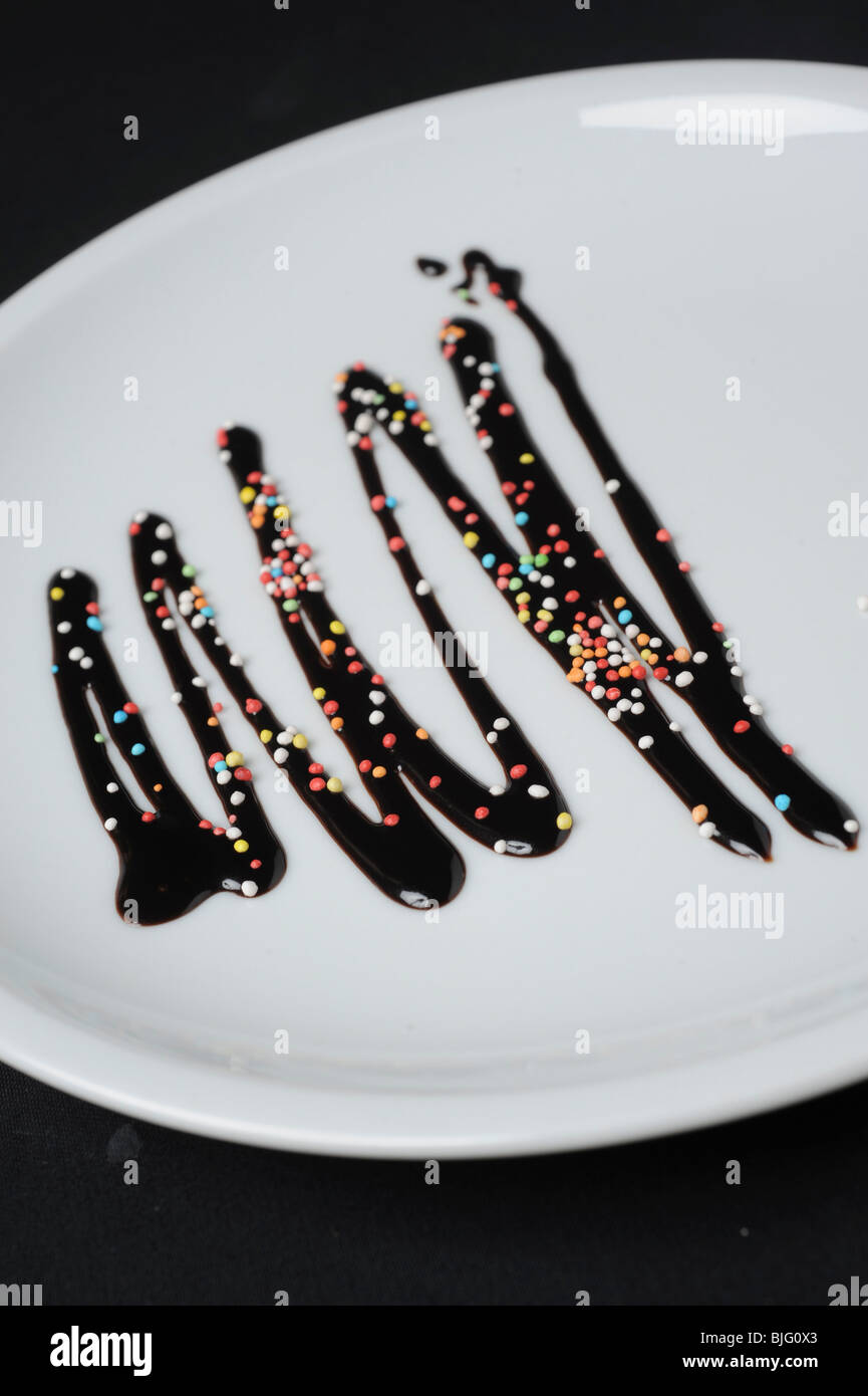 Plate decorated with chocolate syrup and Hundreds and thousands sprinkles Stock Photo