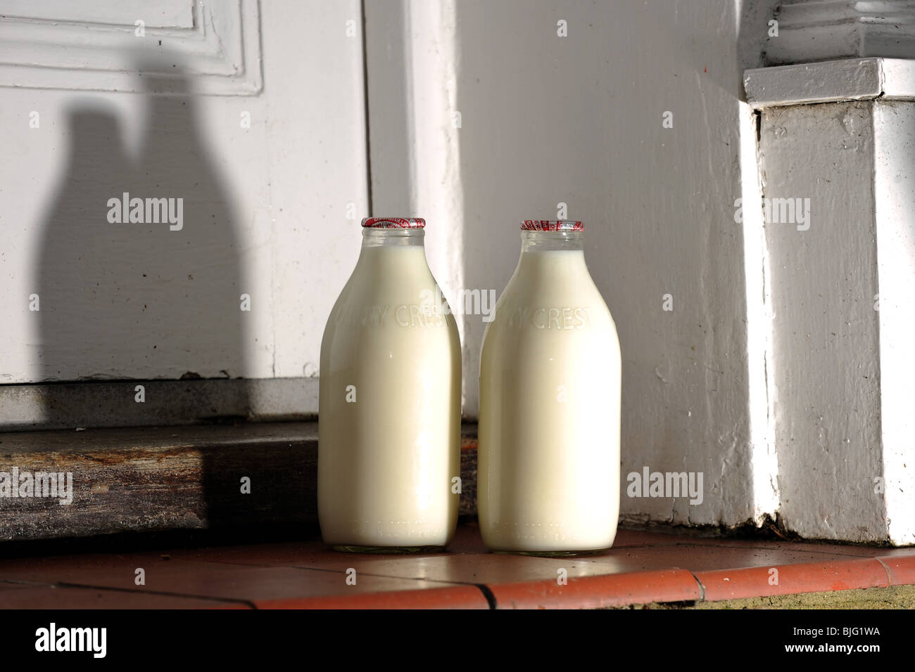 Glass Bottles of milk on a doorstep delivered by milkman UK Stock Photo