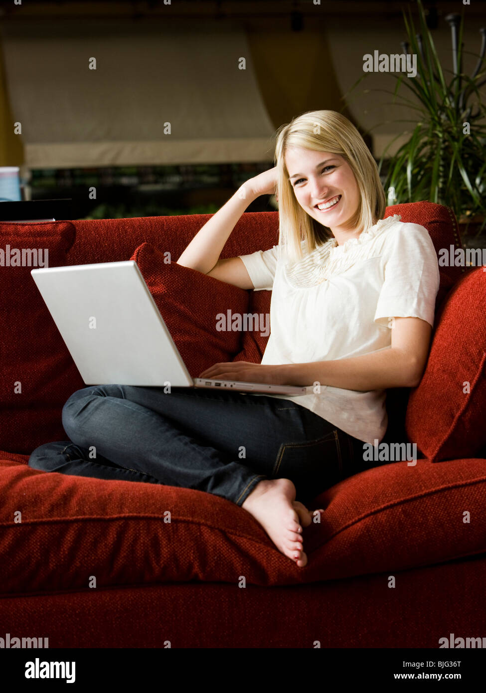 woman using a laptop on a sofa Stock Photo