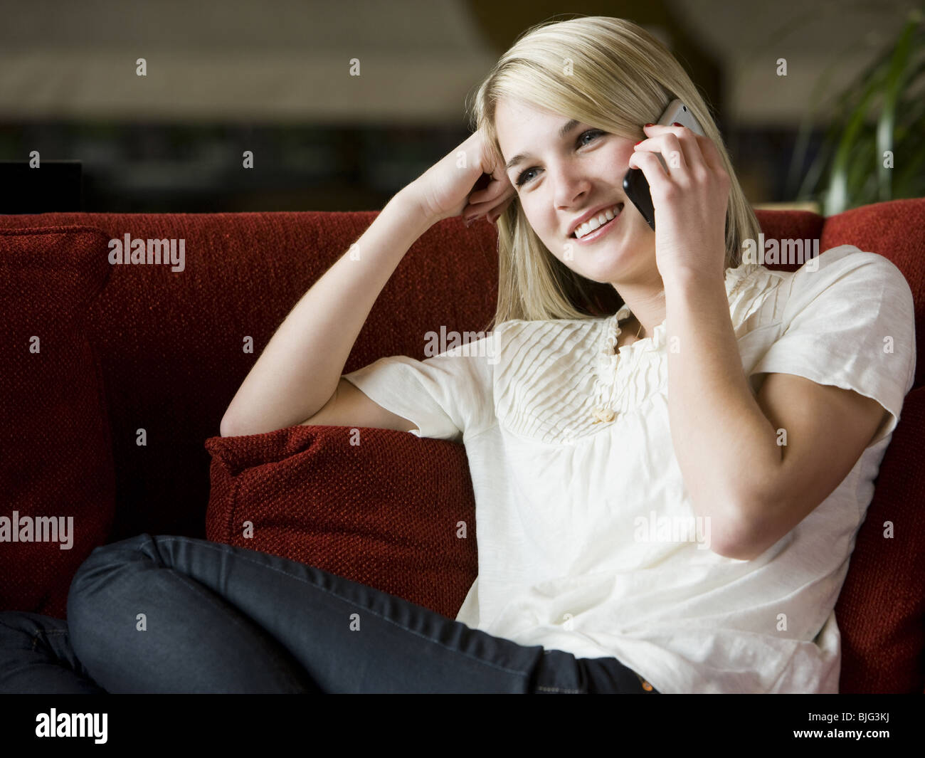 woman using her cell phone on a red sofa Stock Photo
