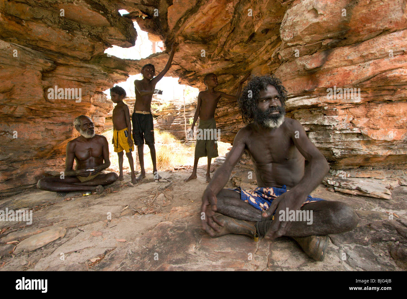 Aboriginal Johnny Pascoe explains to young boys the ancient customs in a rock shelter in their clan country at Mudjawakalal Stock Photo