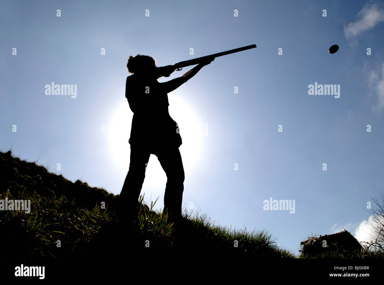 generic silhouette of a female in action shooting clay pigeons with a