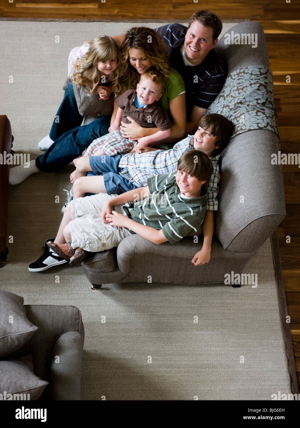 family sitting on sofa in living room Stock Photo - Alamy