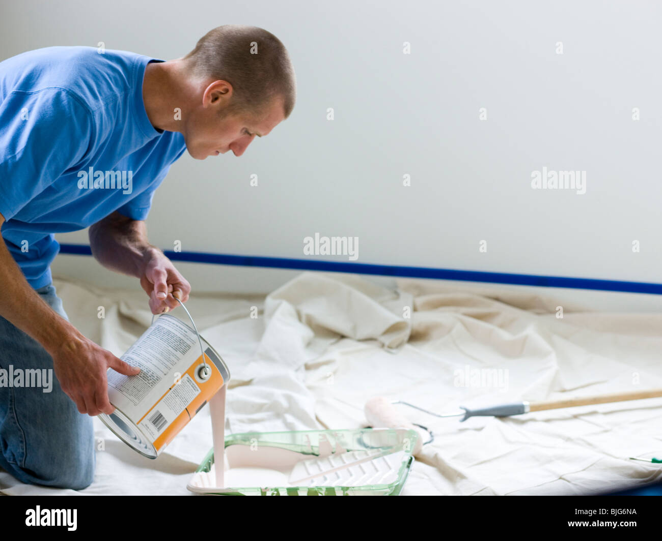 man pouring paint into a roller tray Stock Photo Alamy