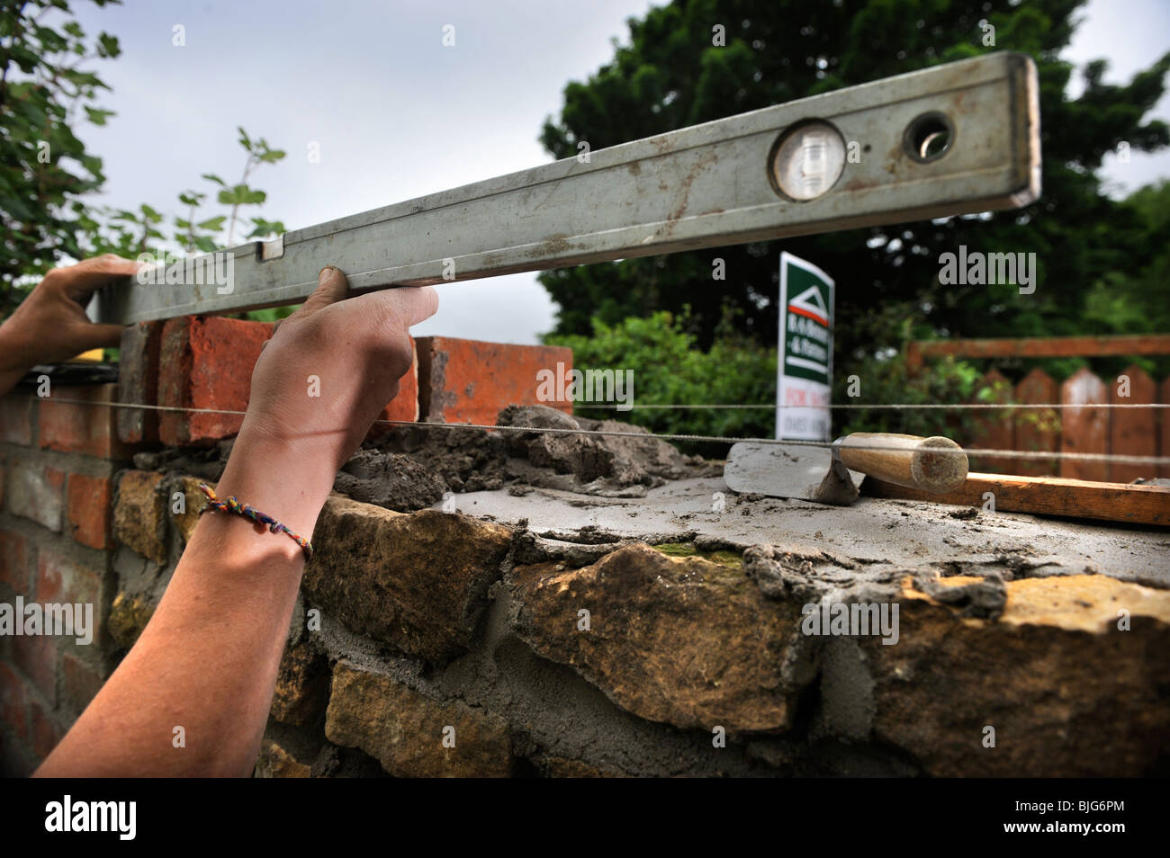 Using a spirit level during the building of a garden wall with cotswold ...
