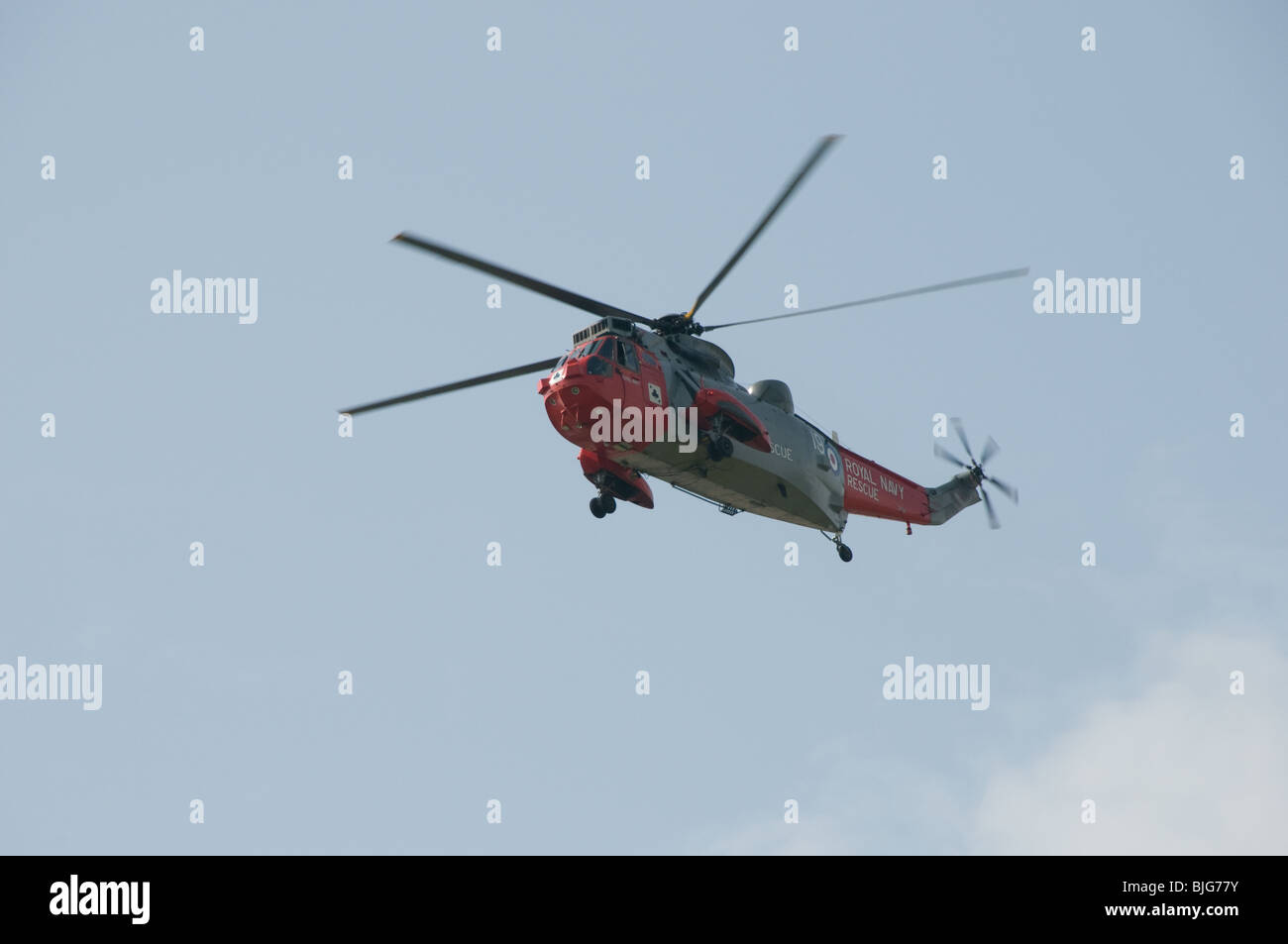 A Royal Navy Westland Sea King Mk V SAR helicopter operated by 771 Squadron flies over the visitor center at RNAS Culdrose. Stock Photo