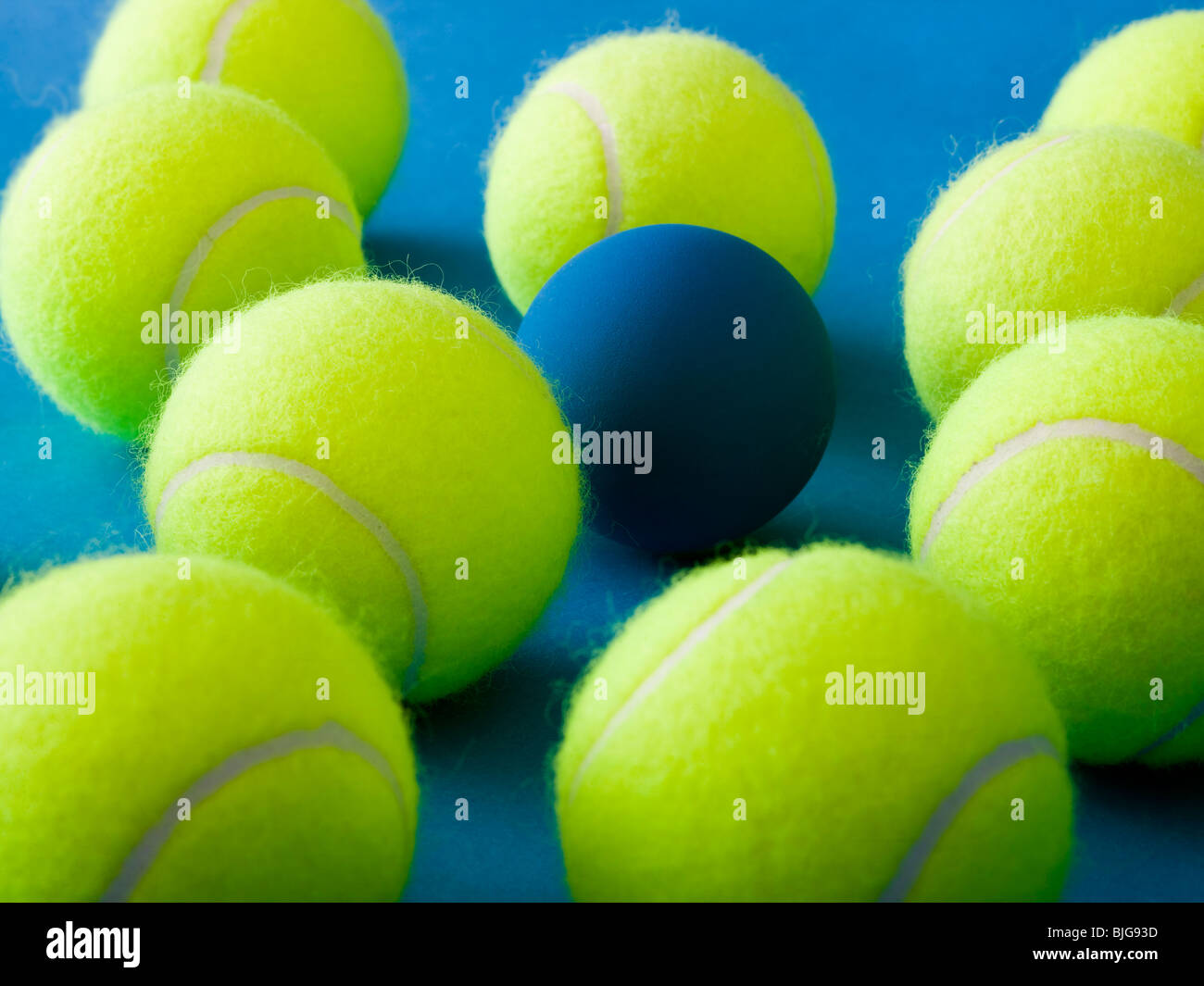 tennis balls and a racquetball against a blue background Stock Photo - Alamy