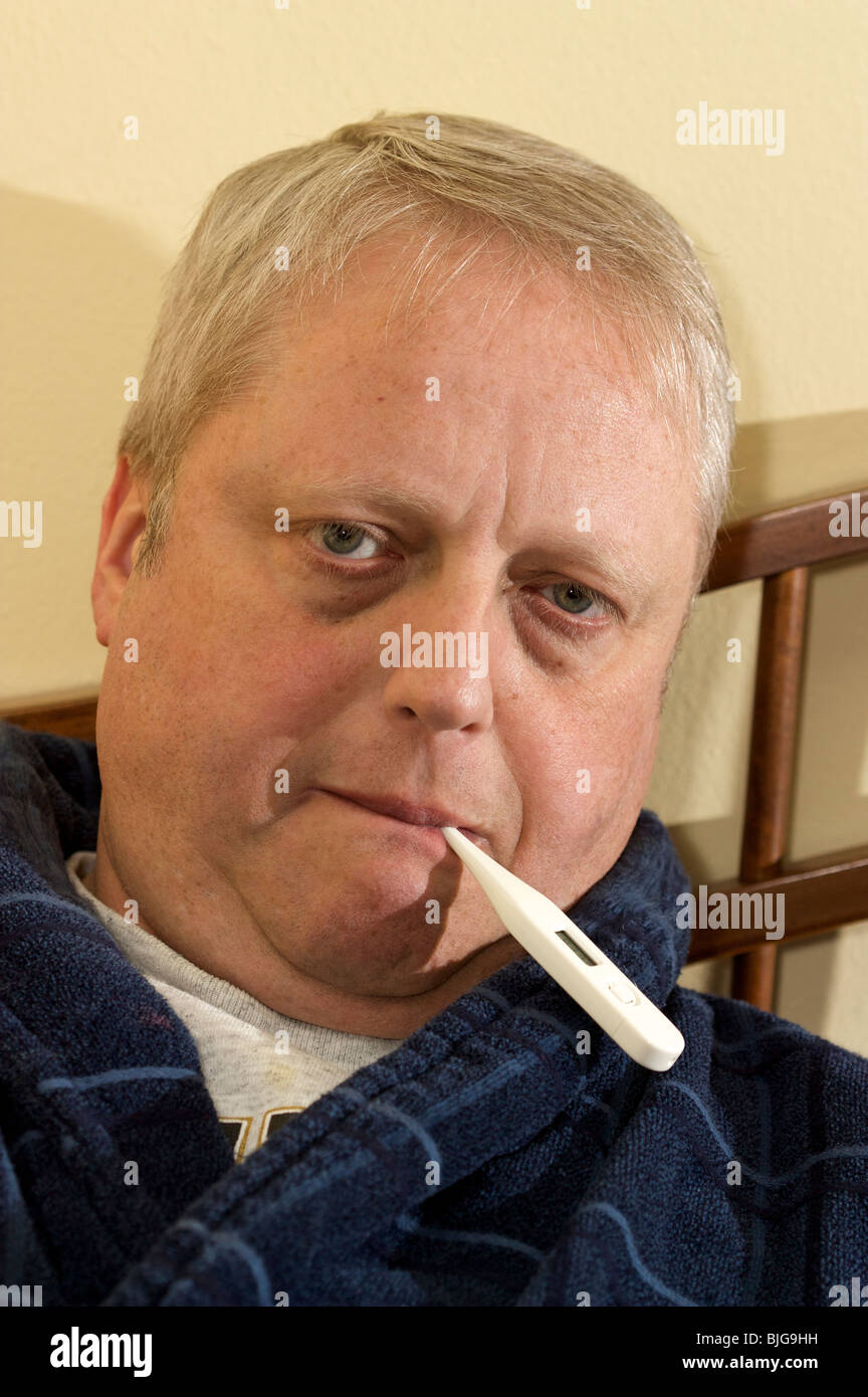 Middle-aged man with oral digital thermometer in mouth. Stock Photo