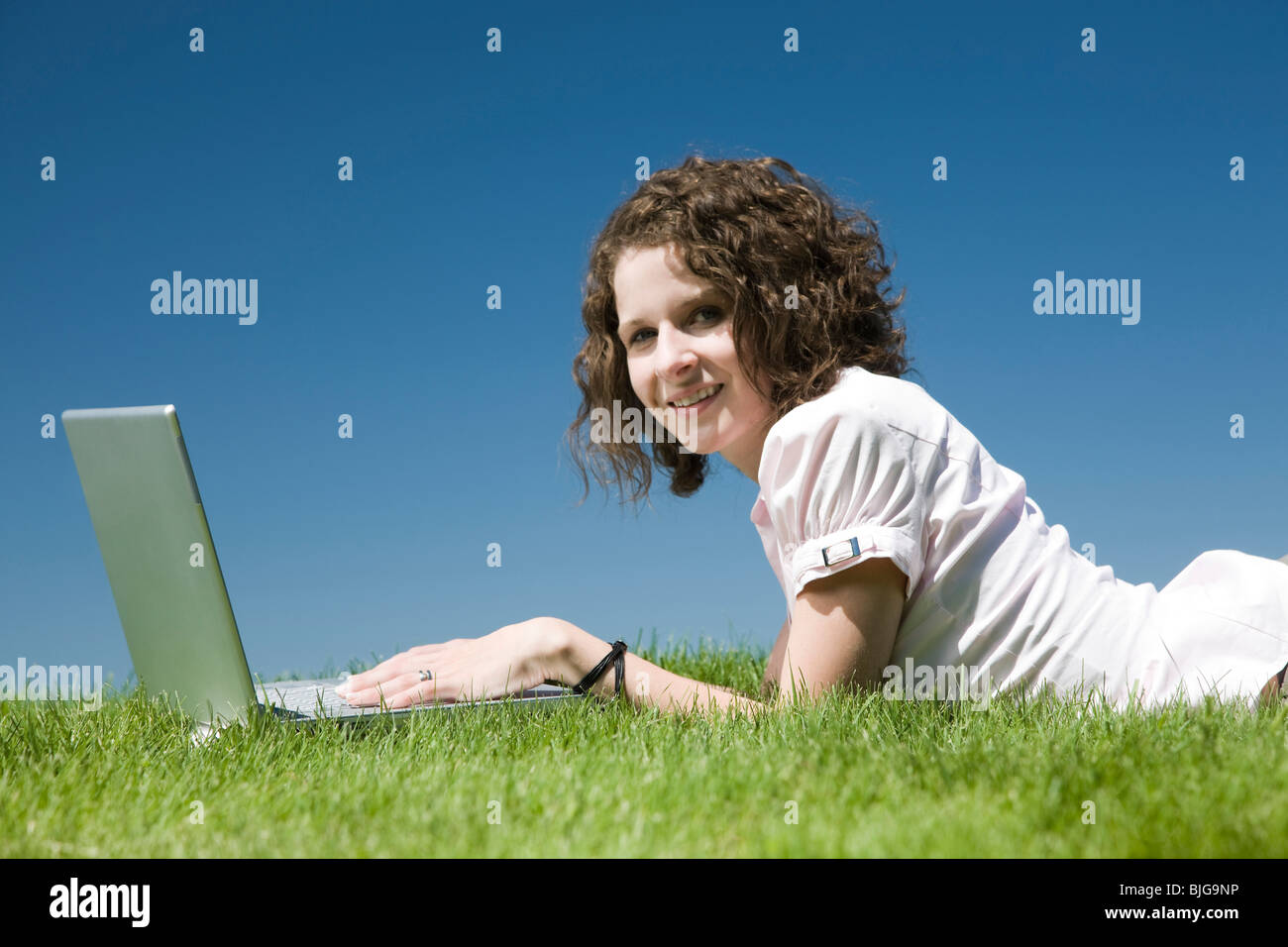 woman lying on the grass using a laptop Stock Photo - Alamy