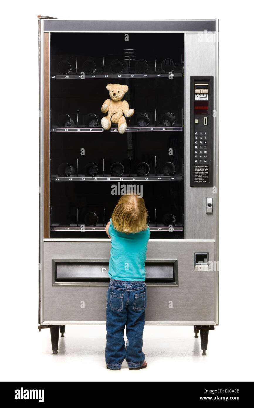 girl buying a teddy bear from a vending machine Stock Photo