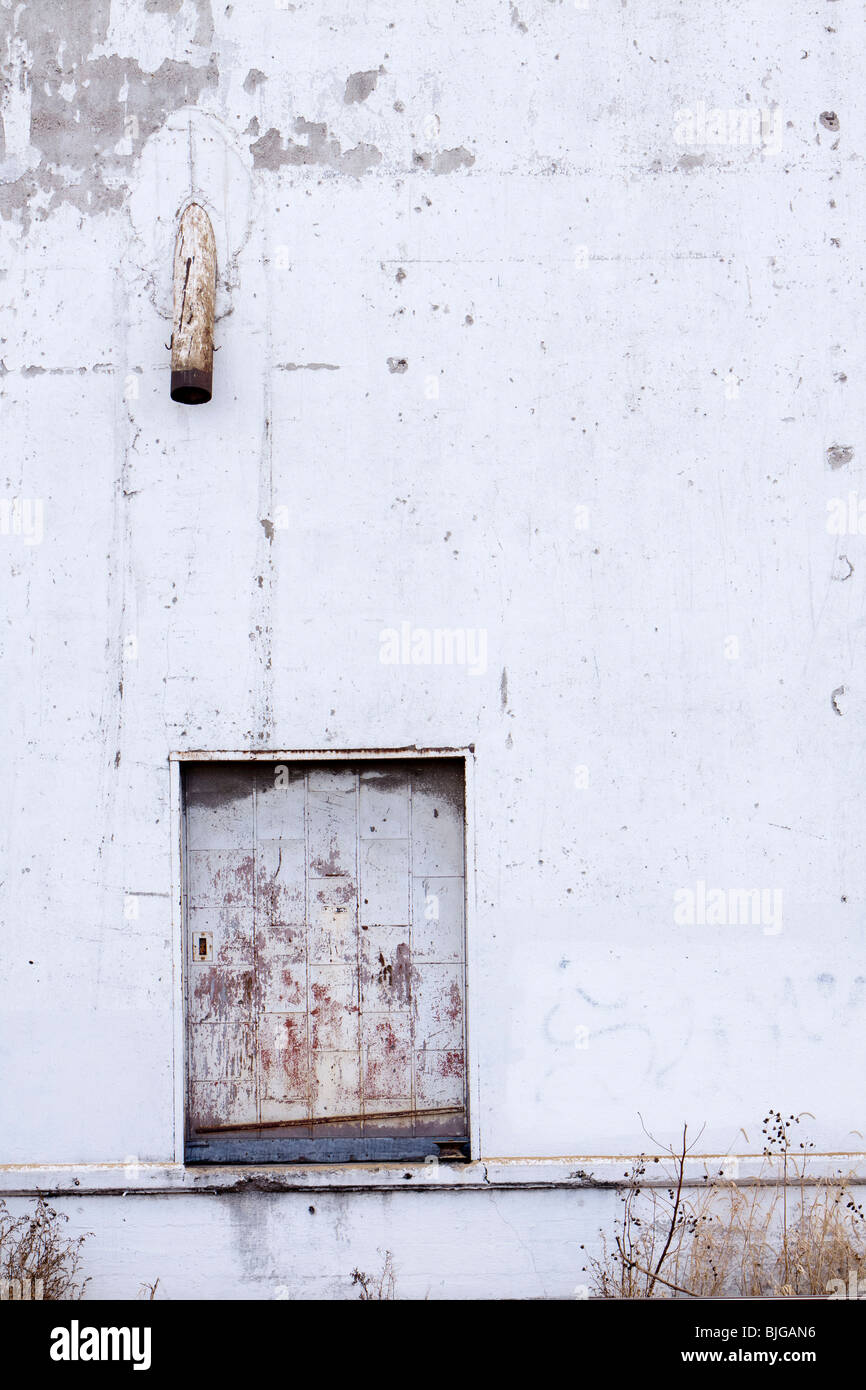 A dirty door and dirty face of an agricultural building in rural Nebraska, USA. Shot from public sidewalk. Stock Photo