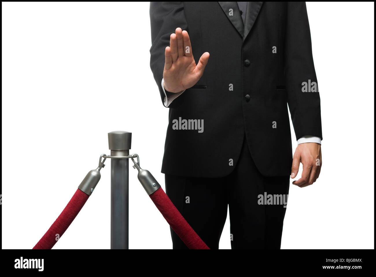 man in a tuxedo denying entry through a velvet rop Stock Photo