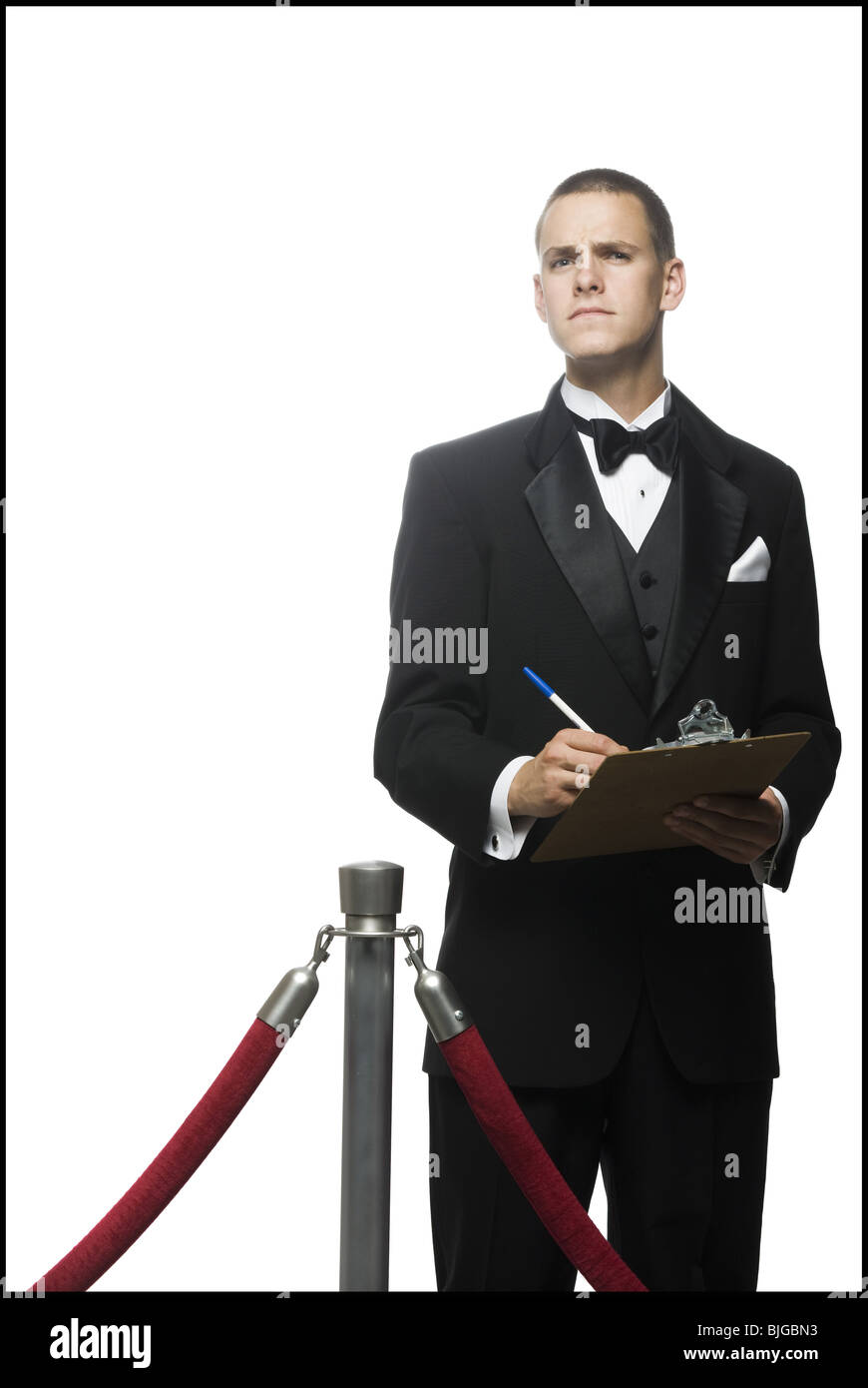 man in a tuxedo next to a velvet rope Stock Photo