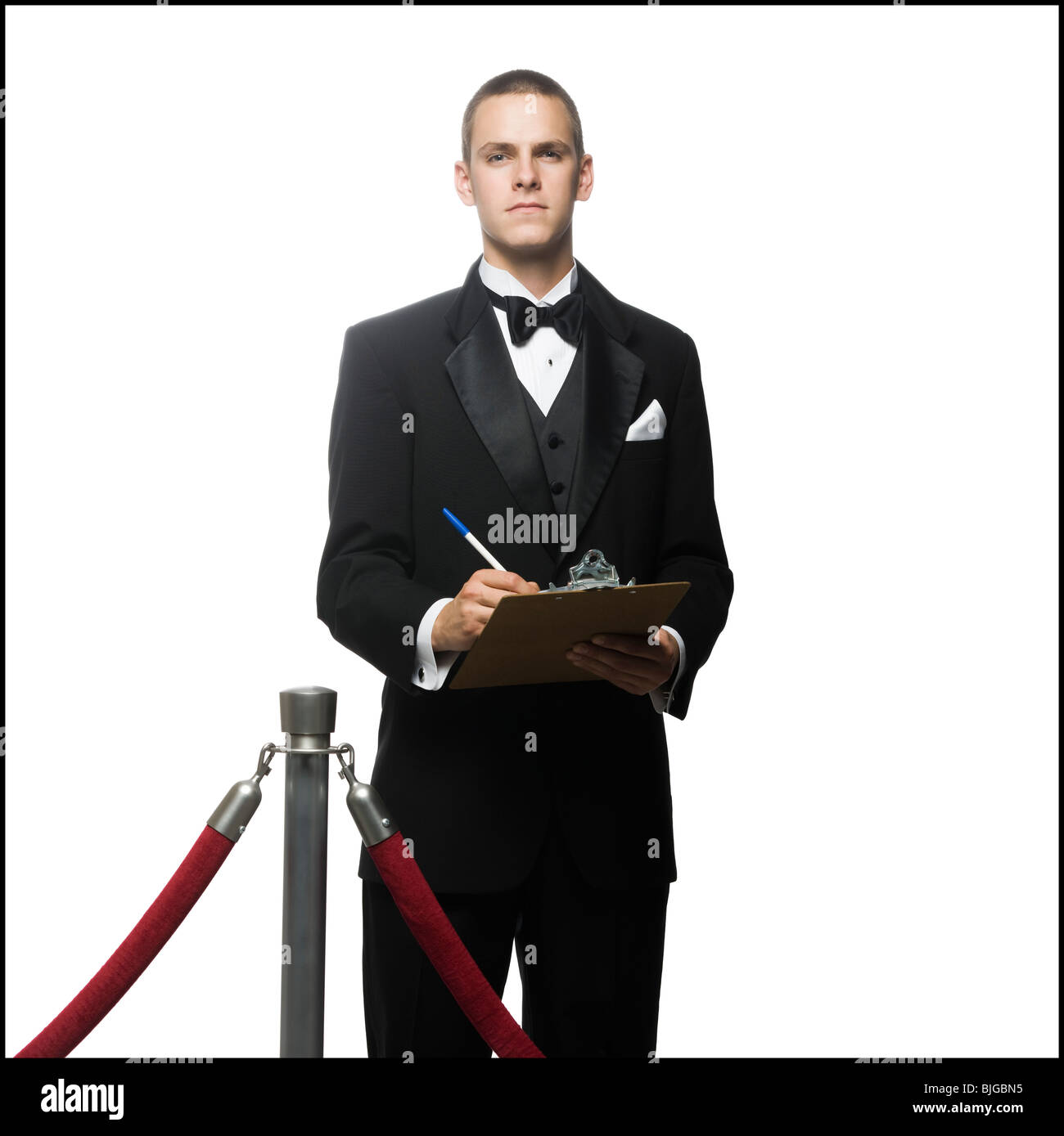 man in a tuxedo next to a velvet rope Stock Photo