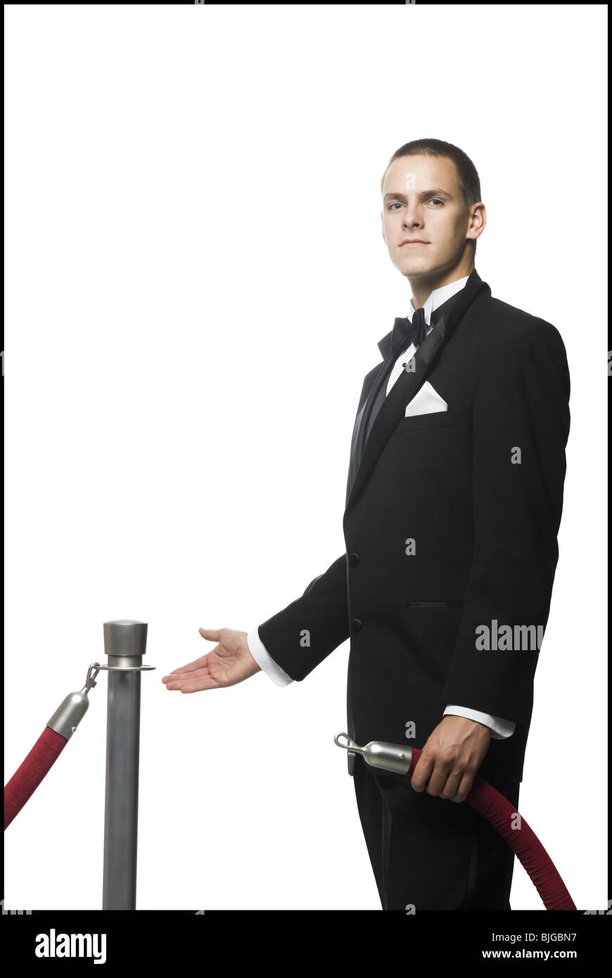 man in a tuxedo next to a velvet rope Stock Photo