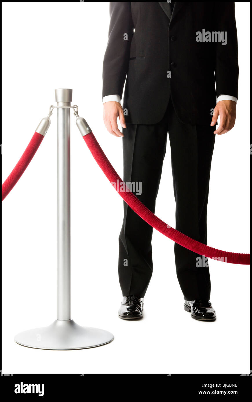 man in a tuxedo next to a velvet rope Stock Photo