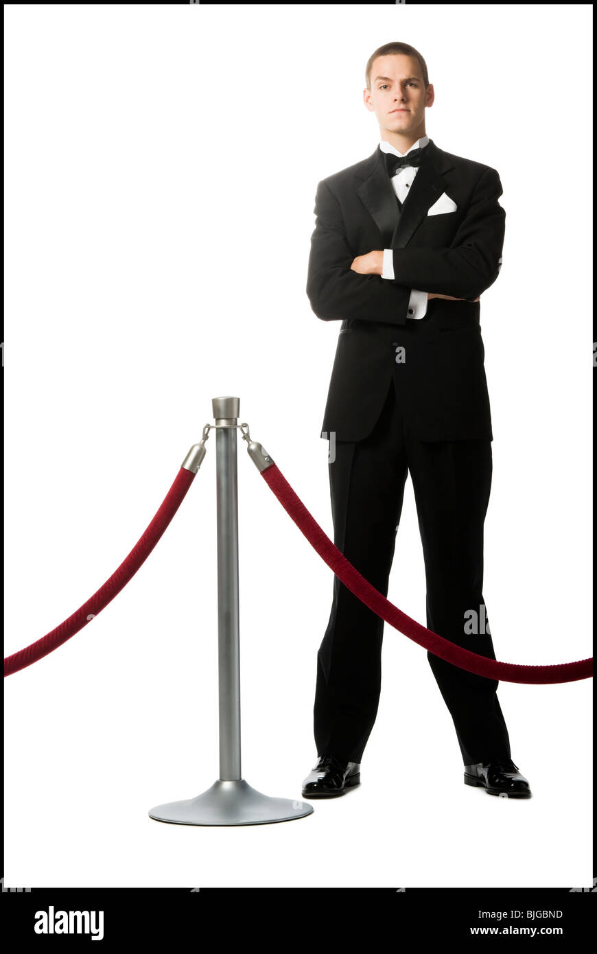 man in a tuxedo next to a velvet rope Stock Photo