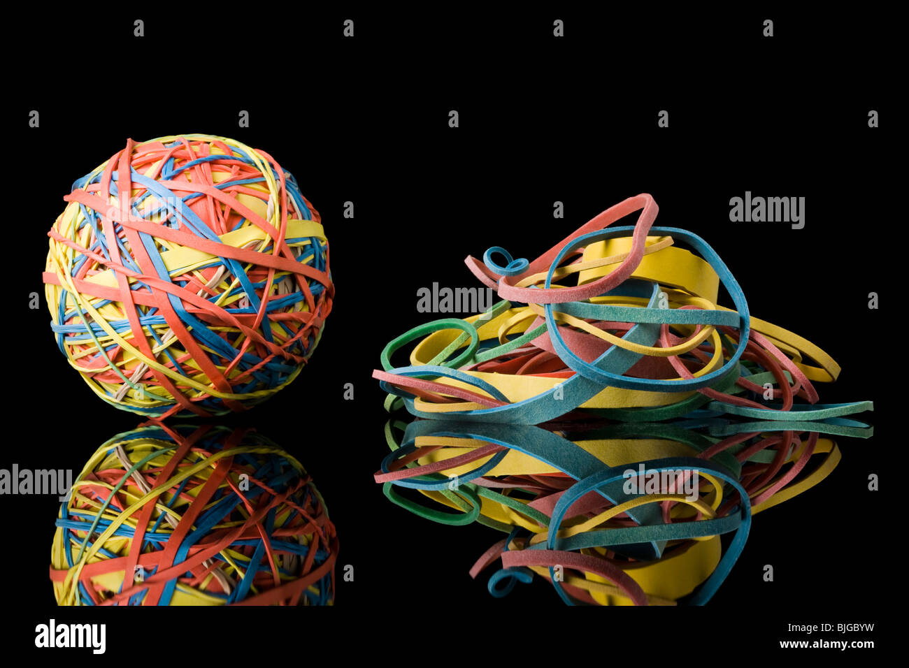 rubber band ball next to a pile of rubber bands Stock Photo