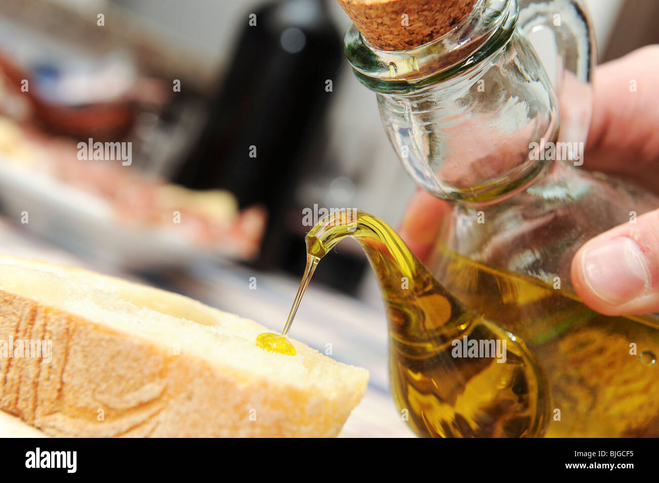 pouring olive oil on a bread slice Stock Photo