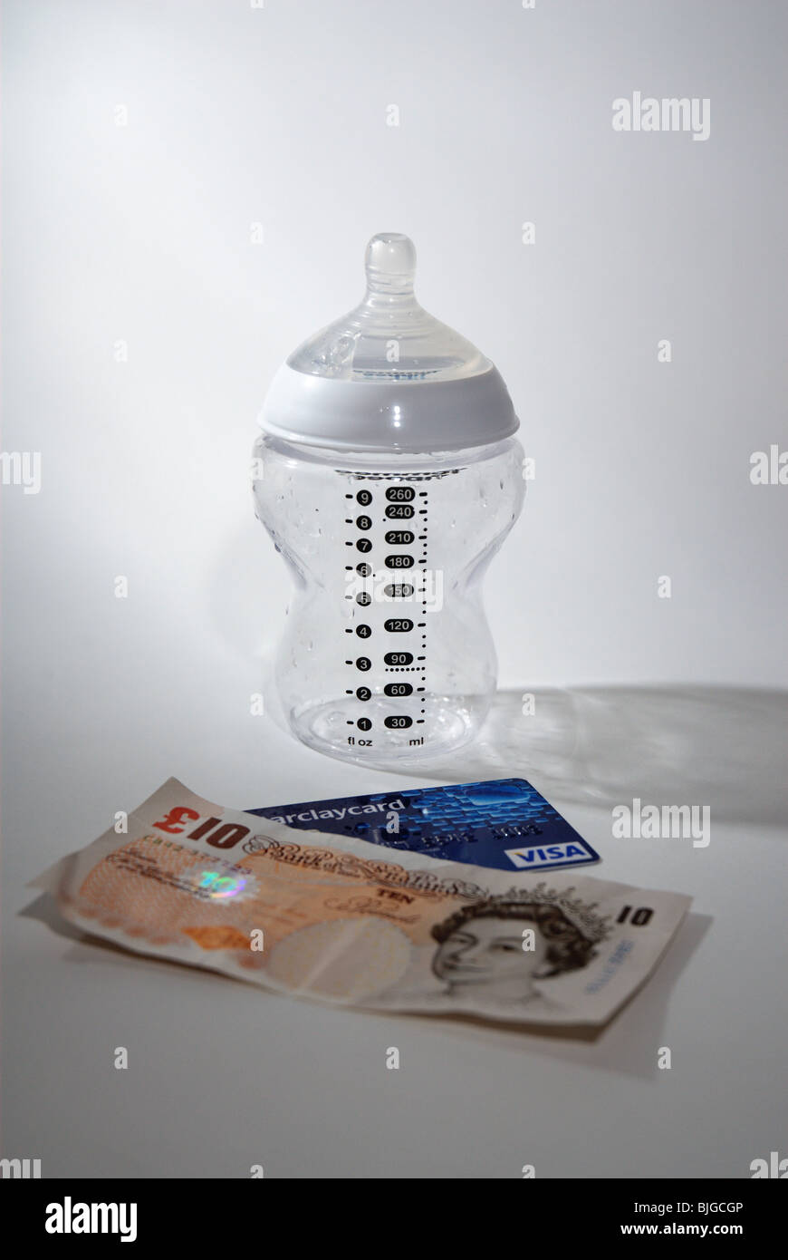 Baby bottle with credit card and UK money to illustrate the cost of having a child and children Stock Photo