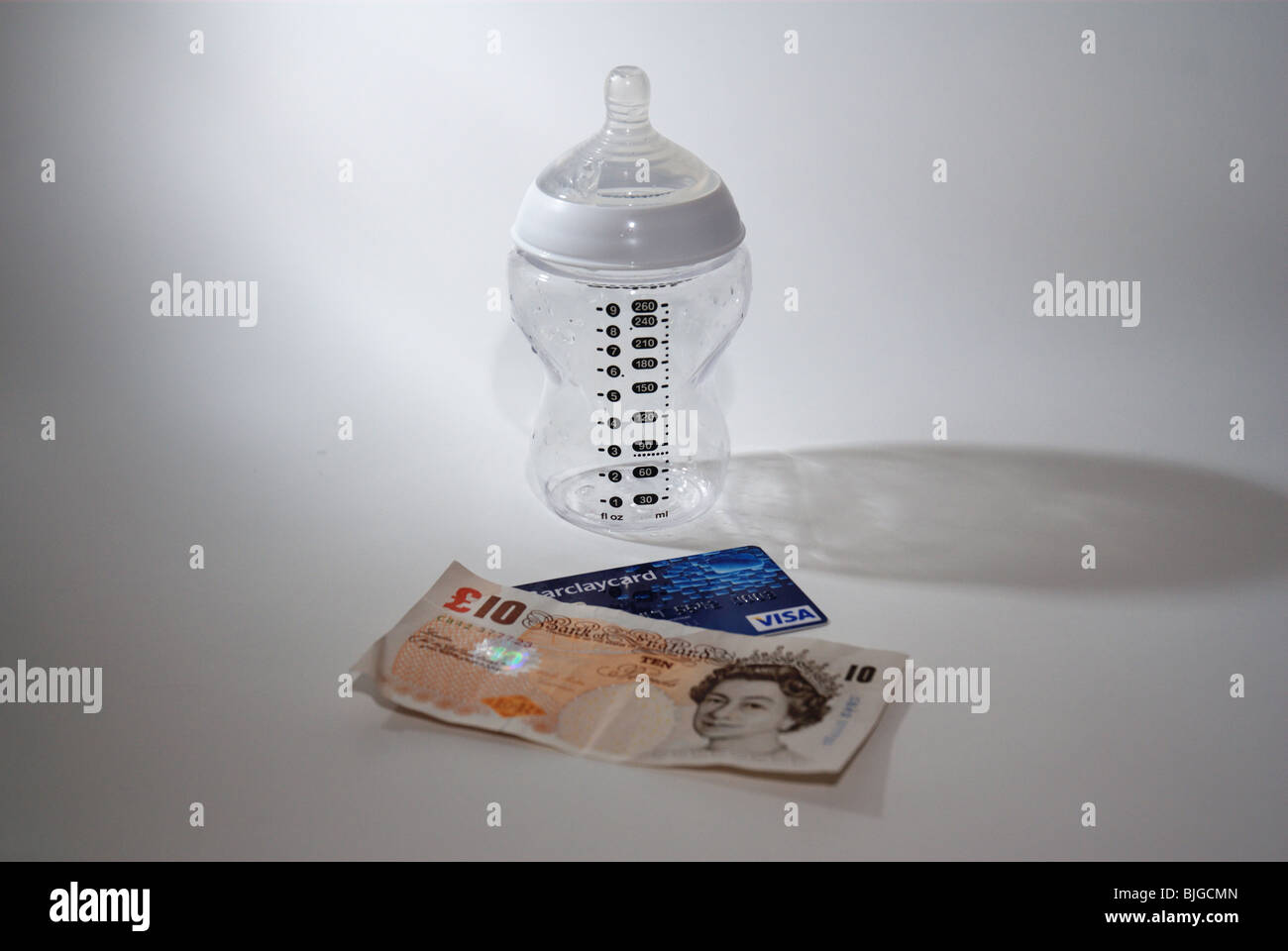 Baby bottle with credit card and UK money to illustrate the cost of having a child and children Stock Photo