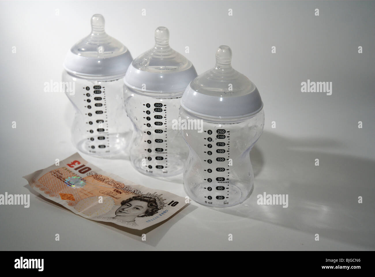 Baby bottle with UK money to illustrate the cost of having a child and children Stock Photo