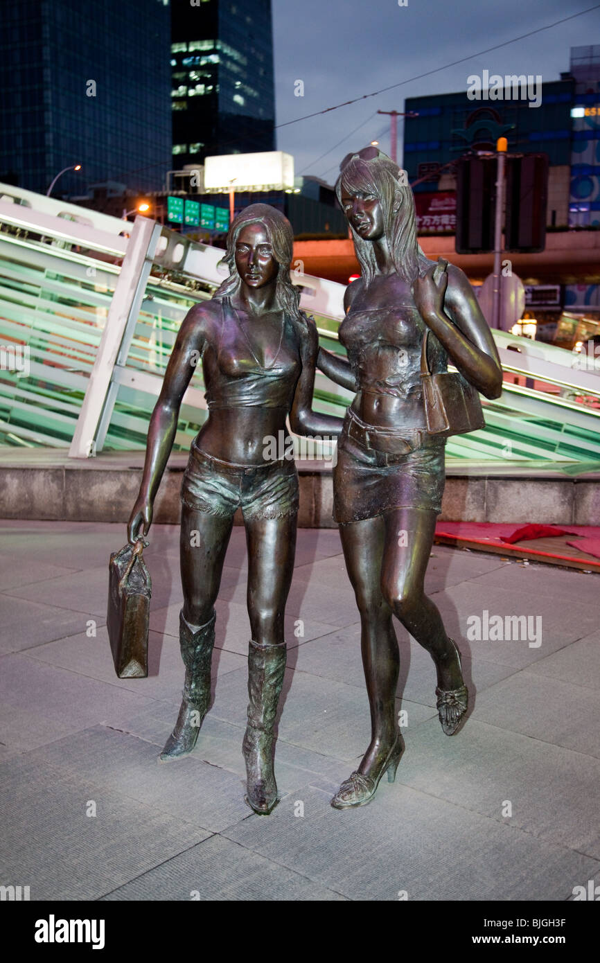 Statues of shoppers outside Orient Shopping Centre at night in Shanghai, China Stock Photo