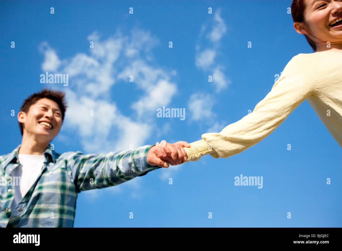 Young couple holding hands against a blue sky Stock Photo - Alamy